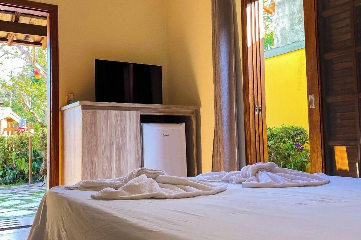 Ein Hotelzimmer mit Bett, Fernseher auf einem Holzschrank und einer Schiebetür zu einem Außenbereich.