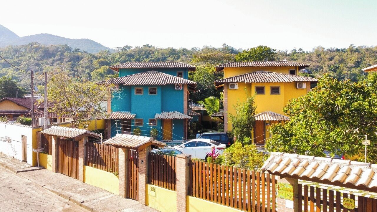 Un quartier résidentiel avec des maisons aux couleurs vives, une clôture en bois et une voiture garée devant.