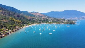 A coastal town with a beach, boats, and mountains in the background. - Recanto das Tiribas (Ilhabela)