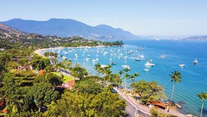 A coastal town with a marina filled with boats, surrounded by lush greenery and mountains in the background. - Recanto das Tiribas (Ilhabela)