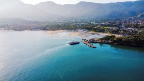 A coastal area with a dock, boats, and a beach. - Recanto das Tiribas (Ilhabela)