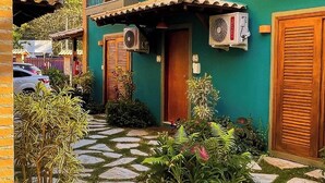 A two-story building with a green facade, a wooden door, and a balcony with a metal railing. - Recanto das Tiribas (Ilhabela)