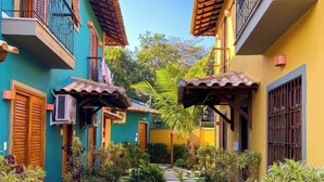 A narrow alleyway with colorful buildings, stone steps, and lush greenery. - Recanto das Tiribas (Ilhabela)
