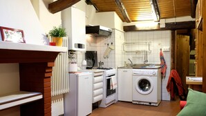 A compact kitchen with a stove, oven, microwave, and washing machine. - Castiglione Lovely Mansarda (Bologna)