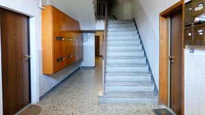 A hallway with a staircase, wooden cabinets, and a mail slot on the right wall. - Marconi Airport Cozy Dream Flat (Bologna)