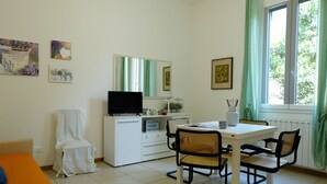 A small, clean room with a bed, a desk, a chair, a television, and a window with curtains. - Marconi Airport Cozy Dream Flat (Bologna)