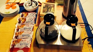 A breakfast buffet setup with various food items, including pastries, fruits, and beverages, arranged on a table in a kitchen area. - Costapicca B&B (Alcamo)