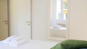 Une chambre d’hôtel avec un lit, un oreiller vert et une fenêtre donnant sur un balcon.