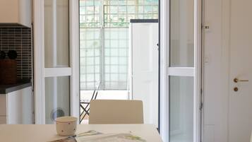 Una habitación con una mesa de comedor, una silla, una puerta blanca y una ventana con vistas a espacios verdes.