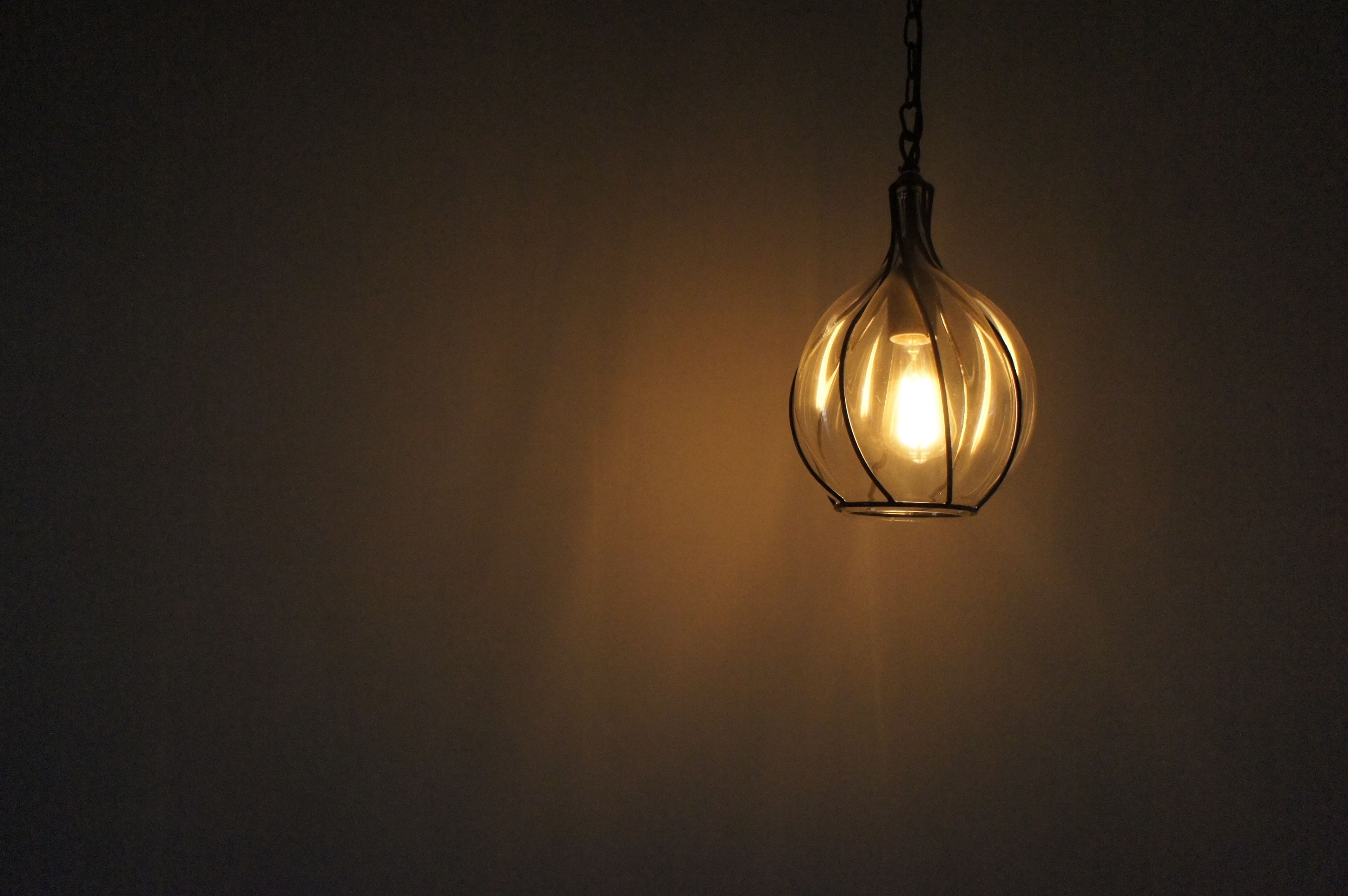 A hanging light fixture with a warm glow against a plain wall.