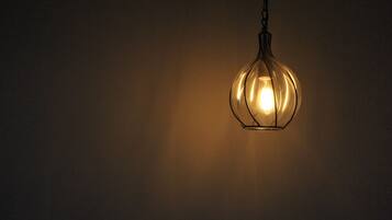 A hanging light fixture with a warm glow against a plain wall.