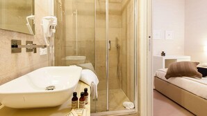 Ein modernes Badezimmer mit einer Glastrennwand zur Dusche, einem großen weißen Waschbecken und einem Spiegel.