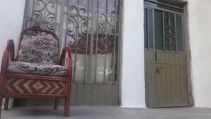 Una silla con un cojín estampado frente a una reja metálica.