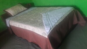 Una cama con una colcha de estampado floral, dos almohadas y una manta blanca.