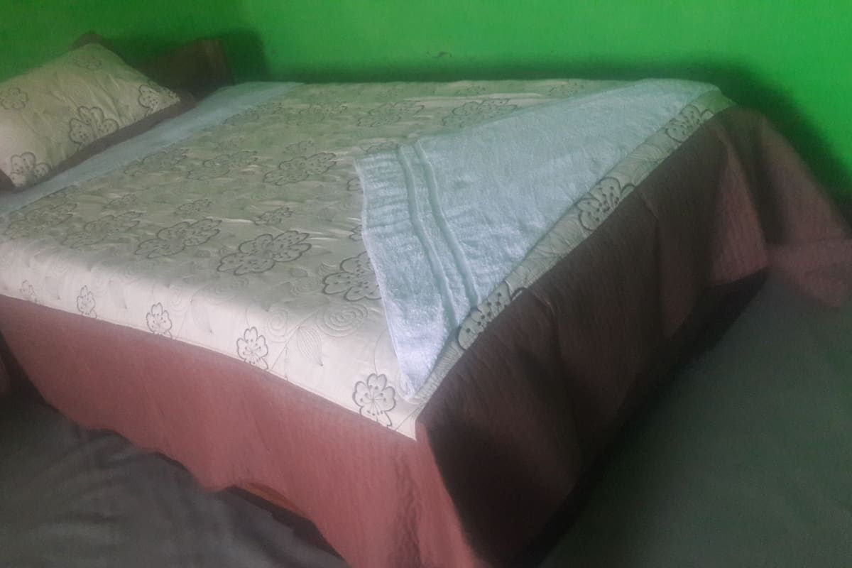 A bed with a floral-patterned bedspread, two pillows, and a white blanket.