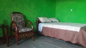 Una habitación con una cama, una silla y una pared verde.