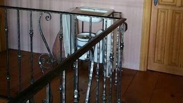 Una escalera con barandilla metálica, una puerta de madera y un ventanal pequeño con una lámpara arriba.