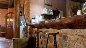 Un coin bar au style rustique, avec un mur en pierre, des tabourets en bois et un luminaire suspendu.