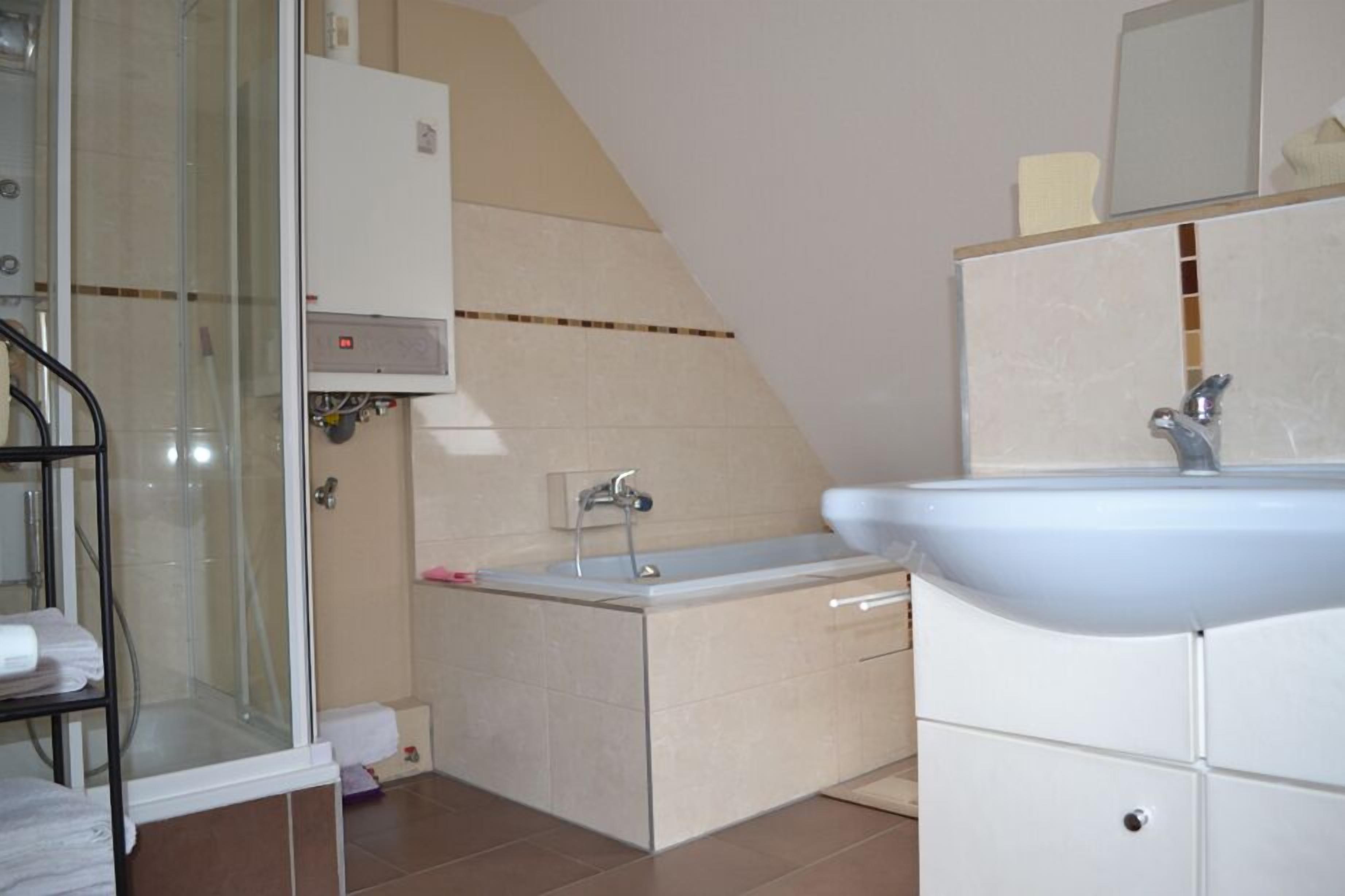 Casa de banho com cabine de duche em vidro, lavatório branco e armário.