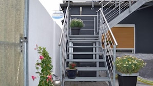 A metal staircase with potted plants at the top and bottom, leading to a building entrance. - Ferienwohnung Resit 2 (Wunstorf)