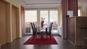 A dining area with a glass table, black chairs, and a red rug. - Ferienwohnung Resit 2 (Wunstorf)