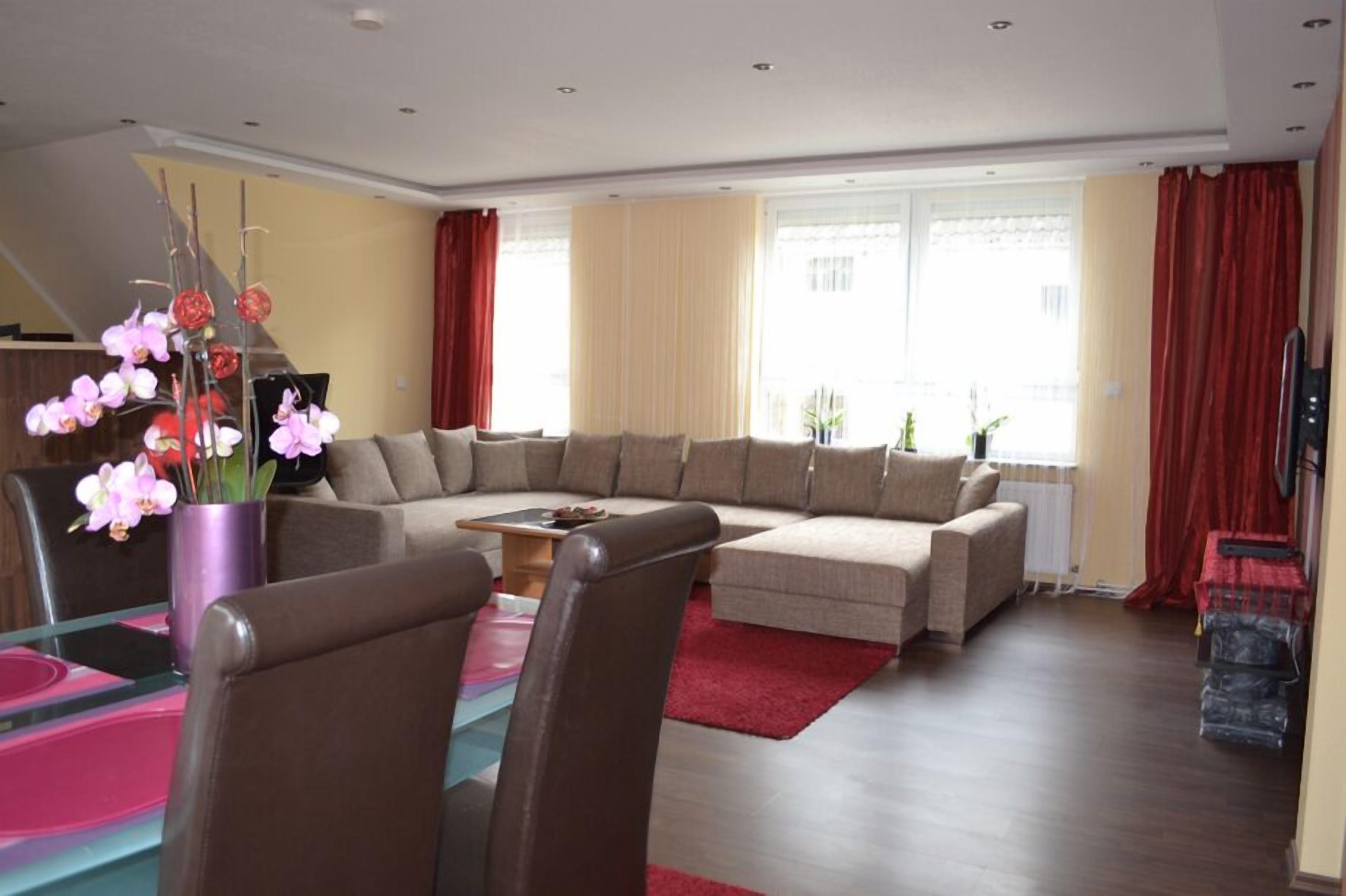 Uma sala de estar moderna com um sofá seccional, uma mesa de centro e um espaço de jantar com cadeiras.