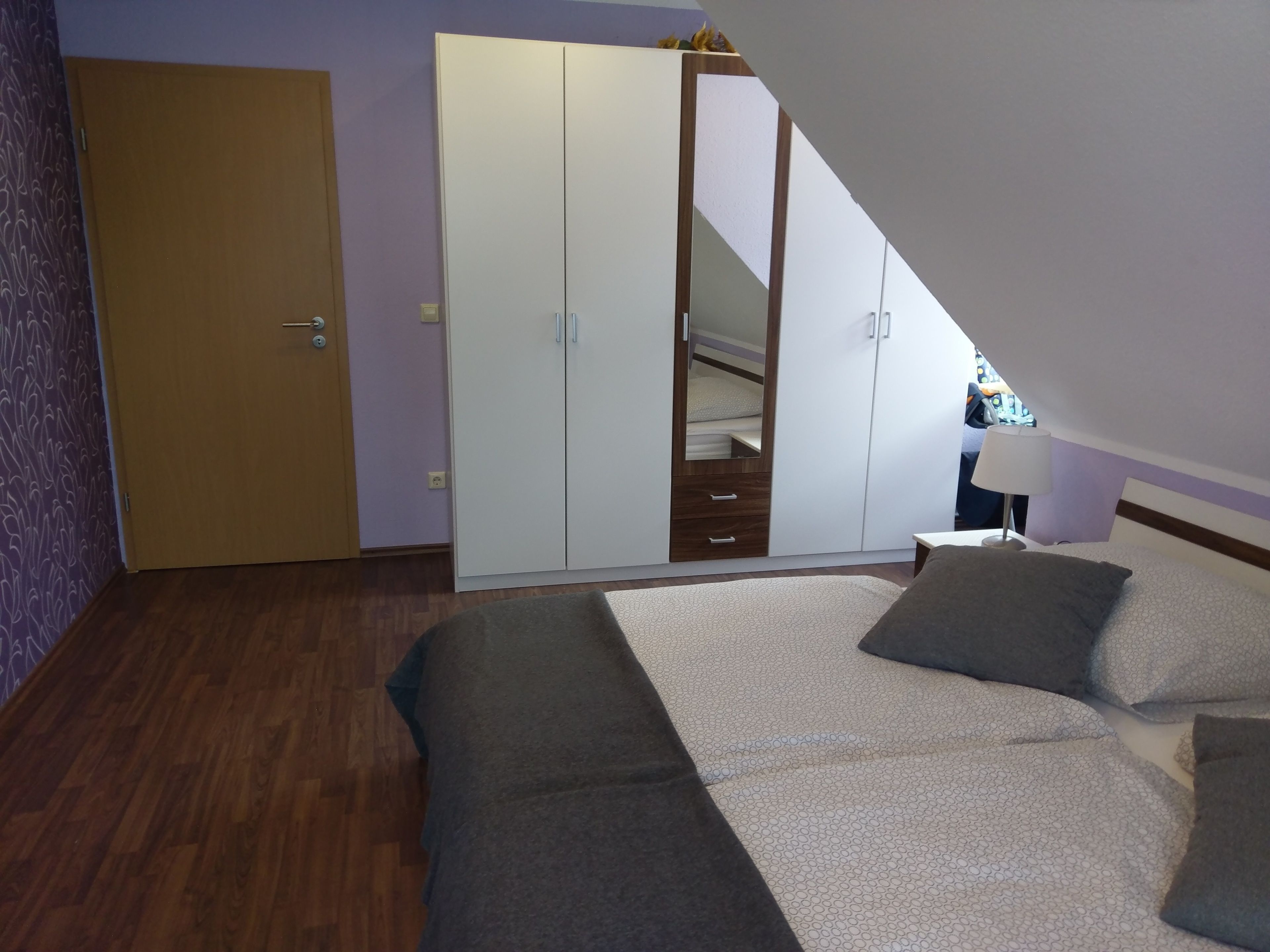Quarto com cama, guarda-roupa e espelho.