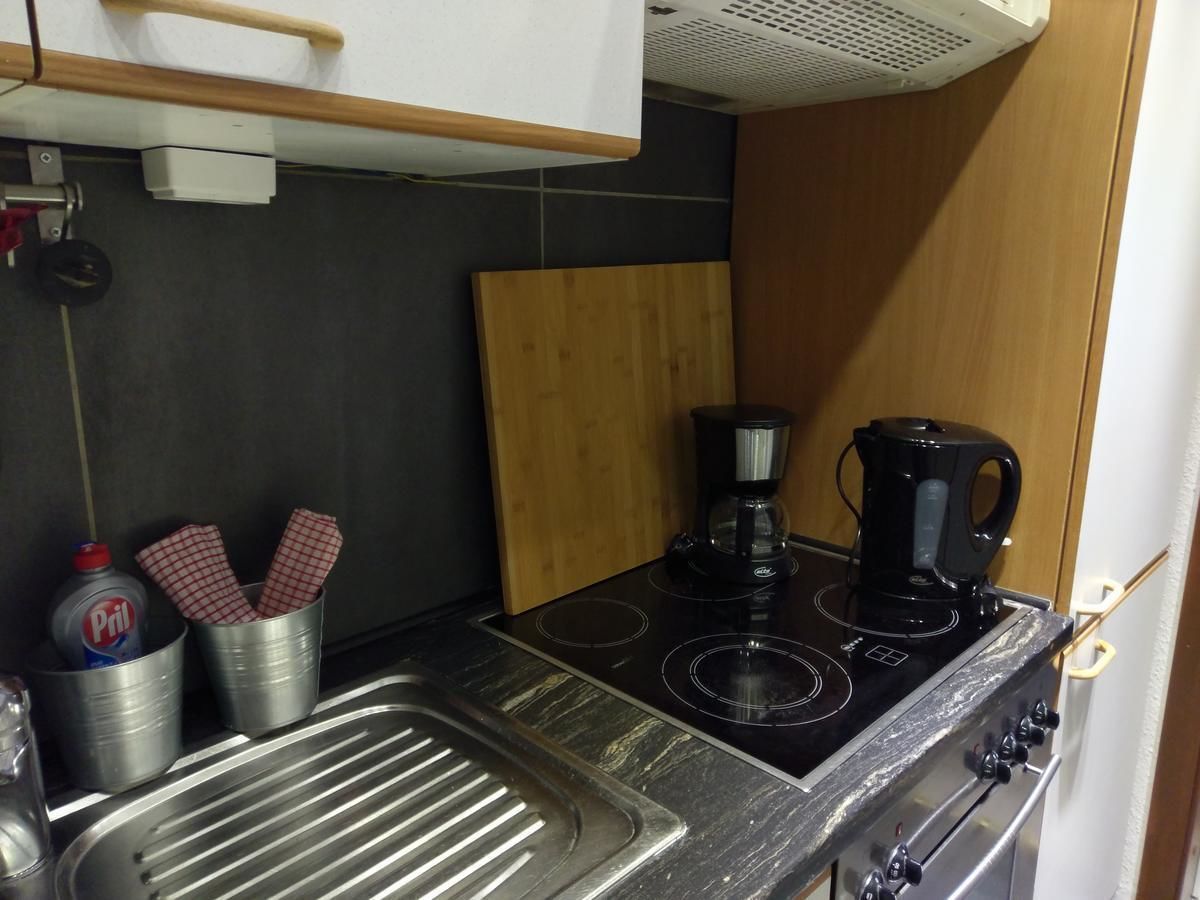 Una cocina pequeña con estufa a gas, cafetera y lavamanos.