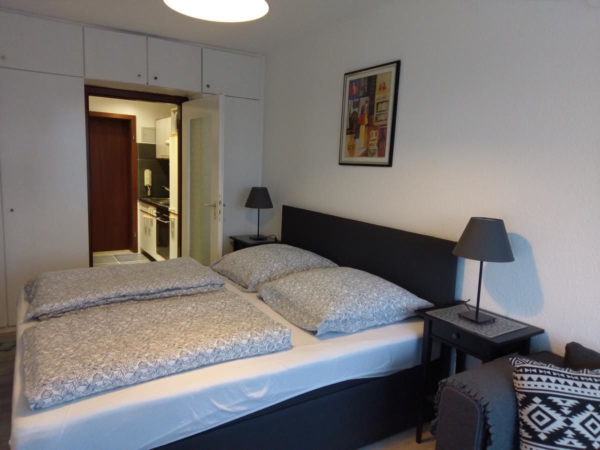 A bedroom with a double bed, two bedside tables with lamps, a chair, and a wardrobe.