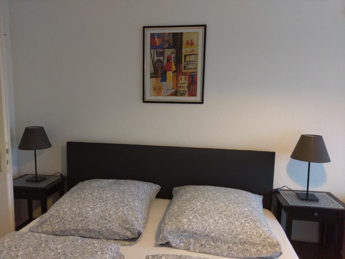 A hotel room with a bed, two nightstands, and a framed picture on the wall.