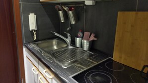 A compact kitchen with a double sink, a stove, and a small countertop area. - Ferienwohnung Resit 5 (Wunstorf)