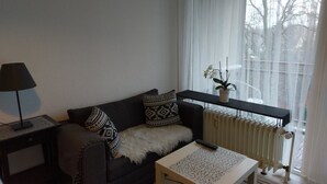 A living room with a sofa, a small table, a lamp, and a radiator. - Ferienwohnung Resit 5 (Wunstorf)
