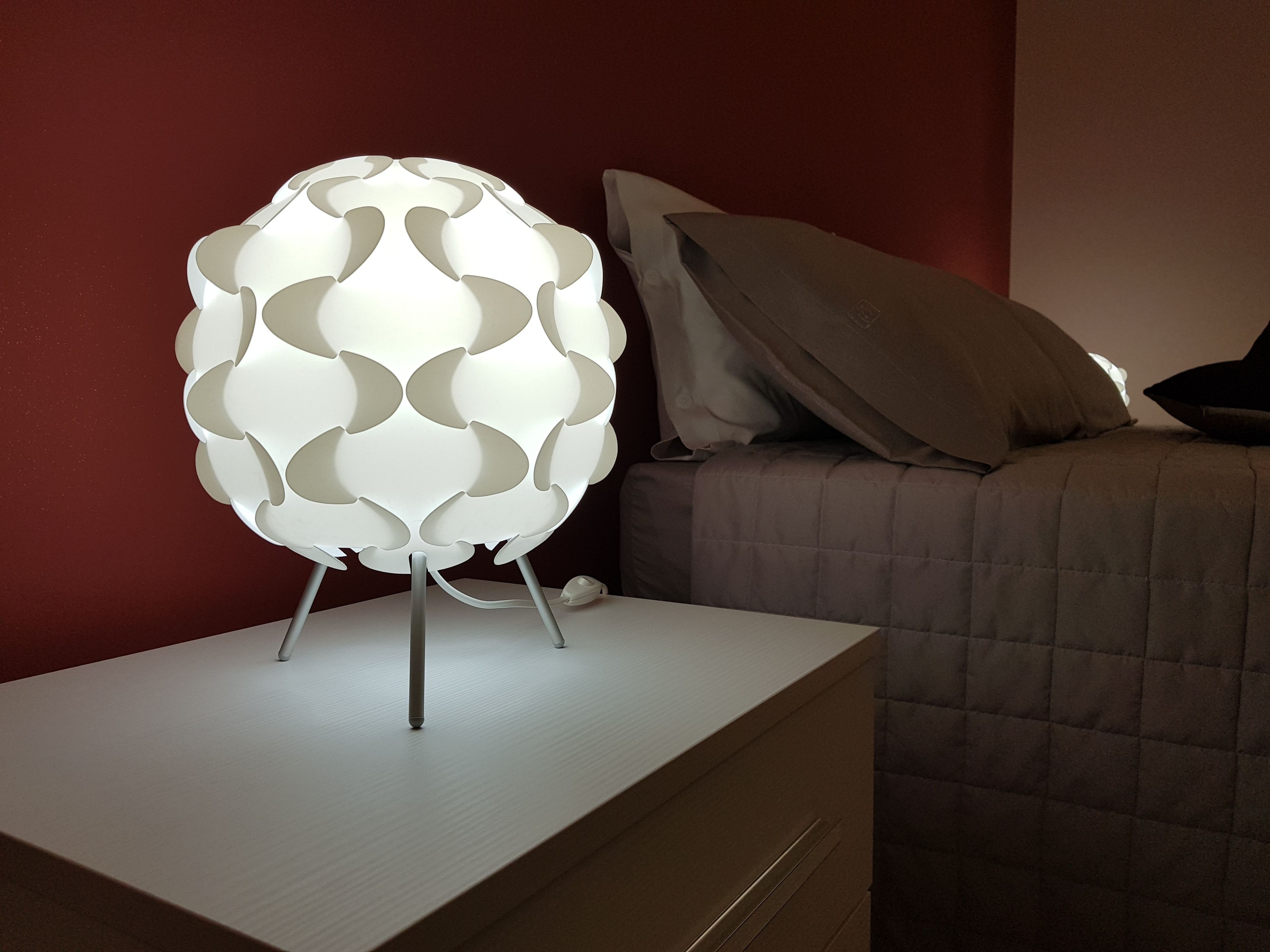 A modern lamp with a spherical design on a bedside table.