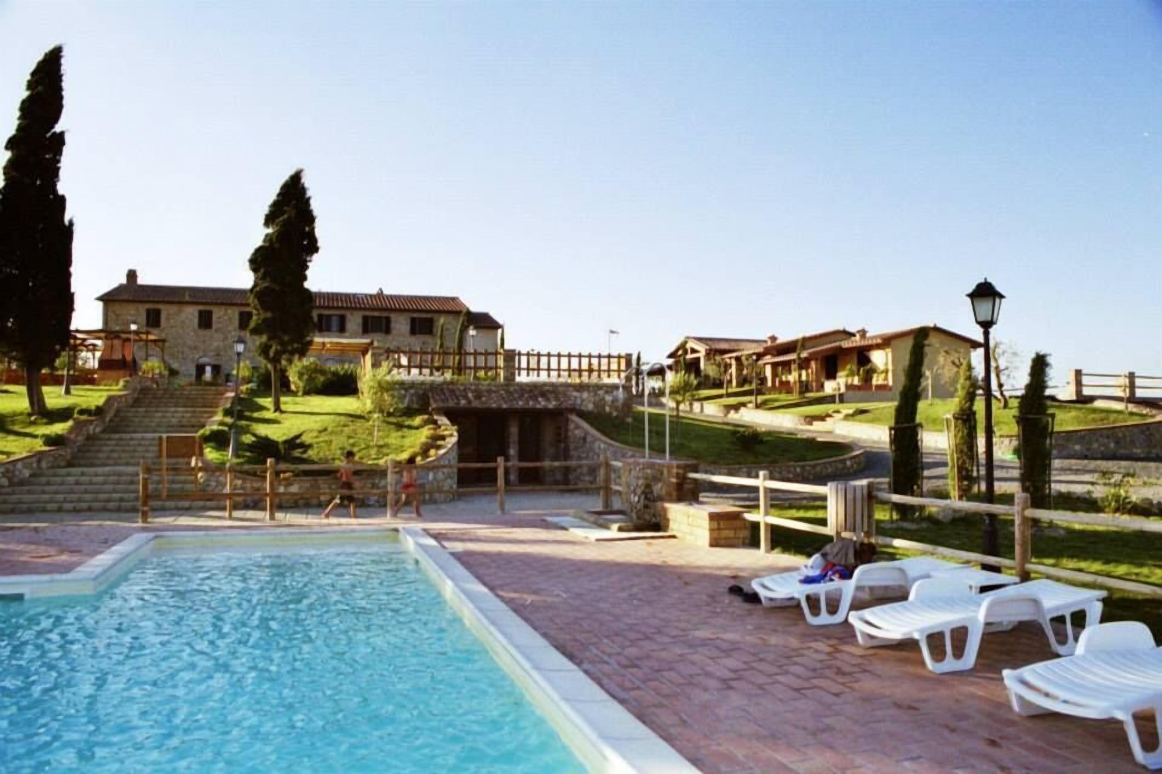 A swimming pool with lounge chairs, a stone building, and a stone staircase leading to a higher level.