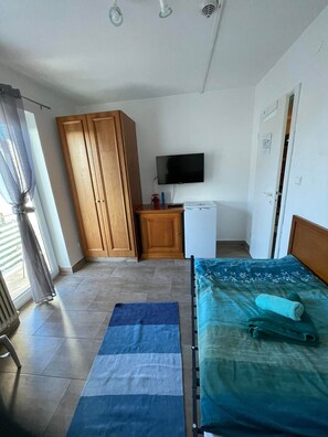 Un dormitorio con cama, televisor, armario y un escritorio pequeño.