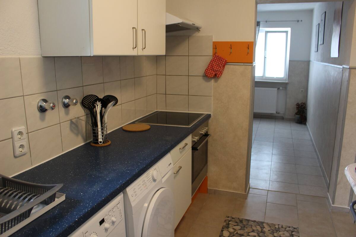 A kitchen with white cabinets, a washing machine, and a countertop with a dish rack.