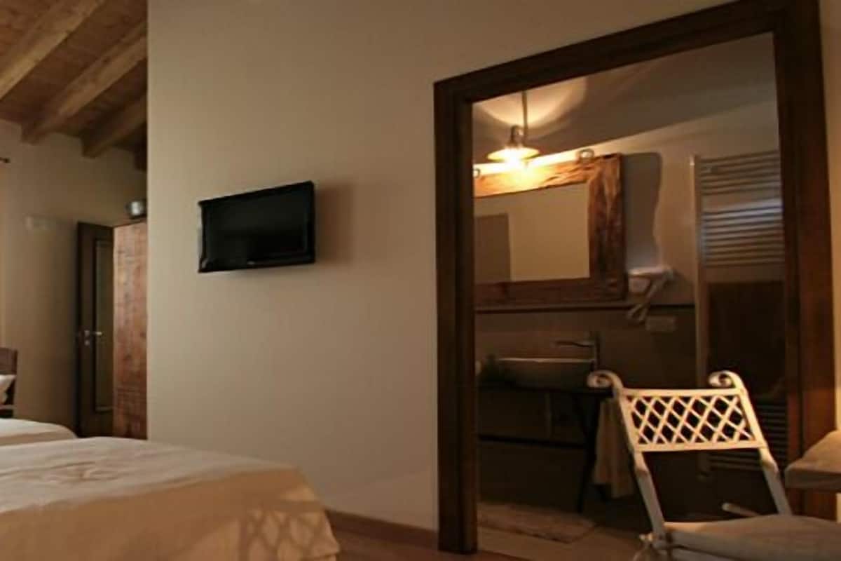 Hotellihuone, jossa on kaksi sänkyä, televisio, peili ja tuoli.