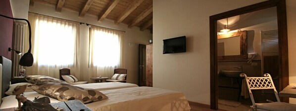 Una habitación de hotel con dos camas, un televisor, un espejo y una silla.