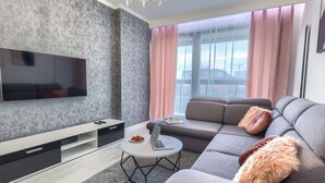 A modern living room with a grey sofa, a flat-screen TV, and a coffee table. - Kazou Residence Burakowska (Warsaw)