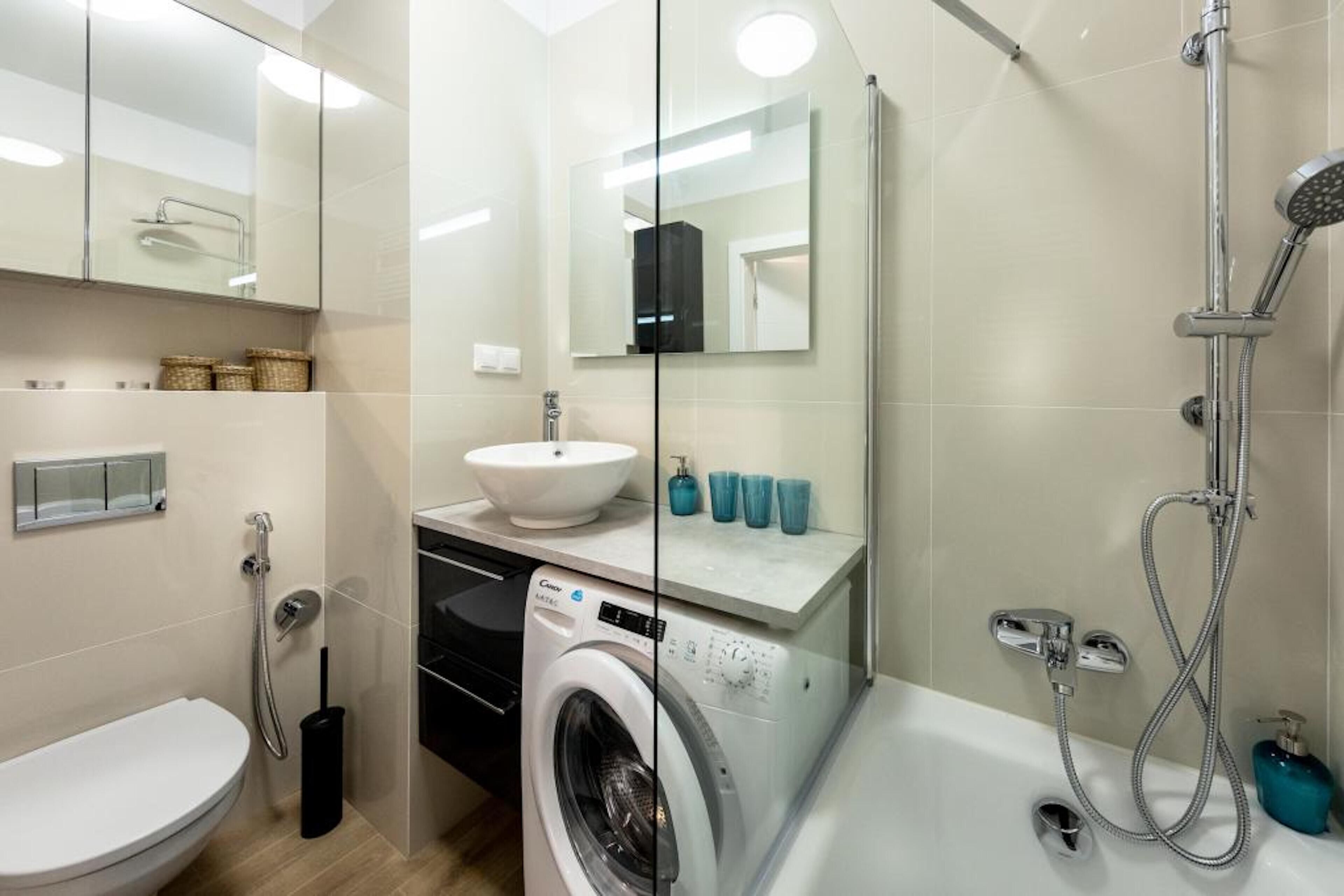 Ein modernes Badezimmer mit Waschmaschine, Waschbecken und Dusche.