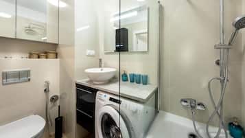 Ein modernes Badezimmer mit Waschmaschine, Waschbecken und Dusche.
