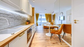 A modern kitchen with a white brick backsplash, wooden countertop, and a dining area with a round table and two chairs. - Kazou Residence Burakowska (Warsaw)