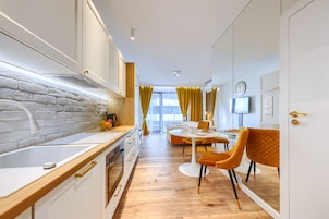 A modern kitchen with a white brick backsplash, wooden countertop, and a dining area with a round table and two chairs.