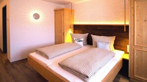 A double bed with checkered bedding, a wooden headboard, and a wall-mounted light fixture. - Berggasthof Sonne Imberg (Sonthofen)