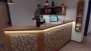 A reception desk with a wooden design, a computer monitor, and a plant. - Berggasthof Sonne Imberg (Sonthofen)