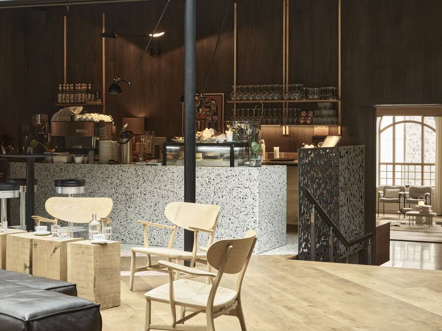Um espaço amplo com teto alto, área de bar, assentos e escada.