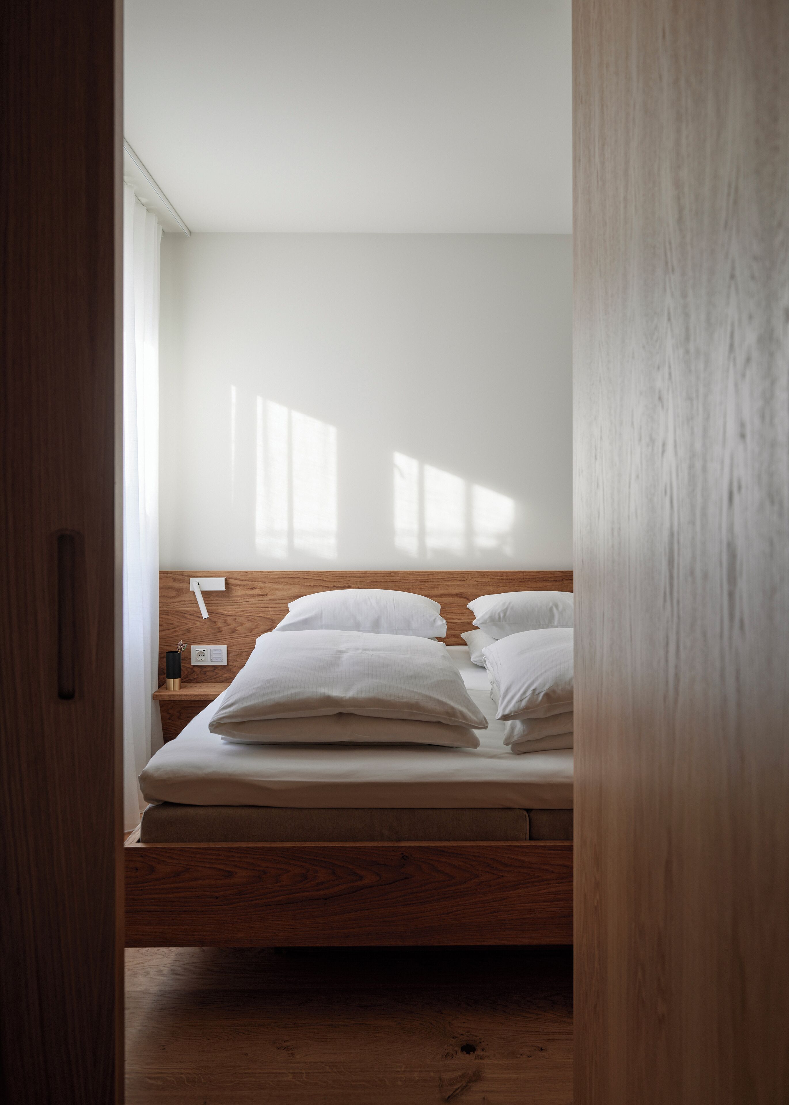 A bedroom with a wooden bed frame, white bedding, and a wooden headboard.