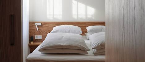 A bedroom with a wooden bed frame, white bedding, and a wooden headboard.