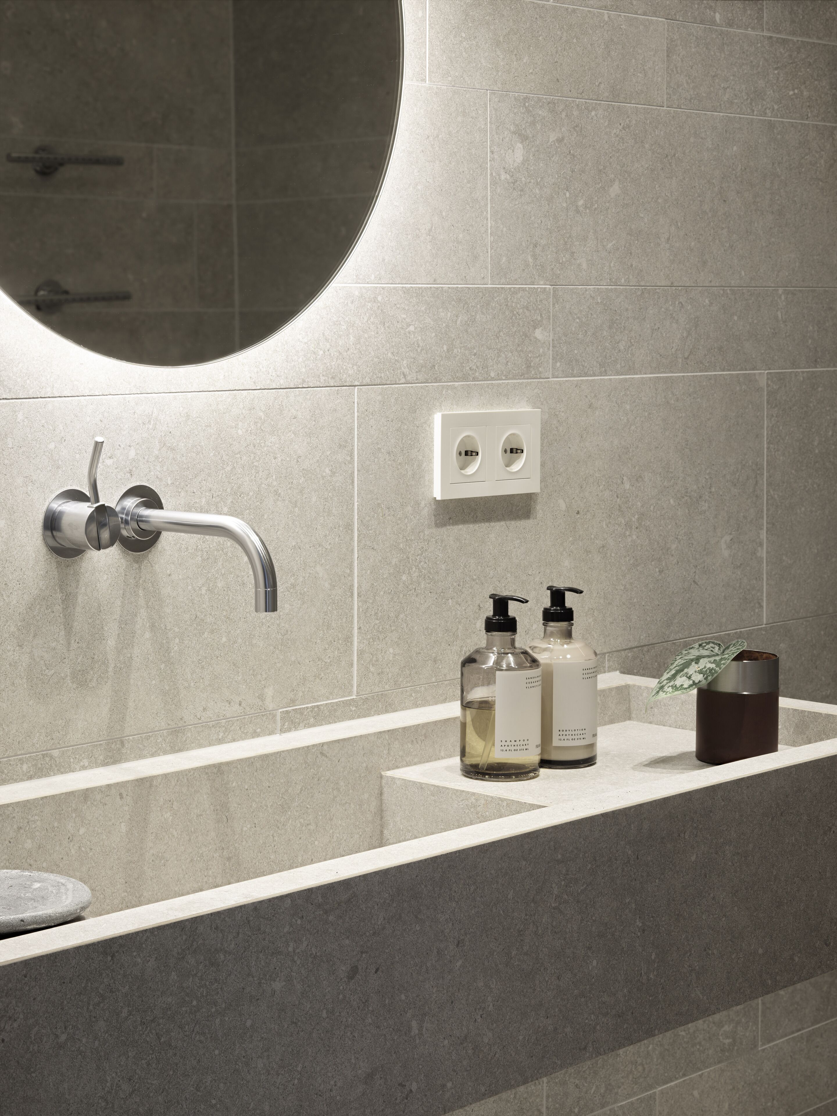 Un baño de diseño moderno, con un espejo grande, un lavabo empotrado en la pared y un estante con artículos de aseo.