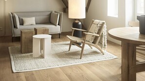 Un dormitorio estilo loft acogedor con vigas de madera a la vista, un ventanal grande, un sofá, una silla, una mesa y una lámpara.